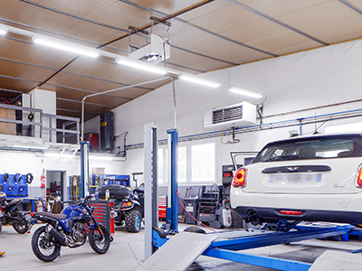 Dans l'atelier du garage automobile diéséliste Delpique, moto bleue et voiture blanche sur le pont d'élévateur, Mini Cooper blanche